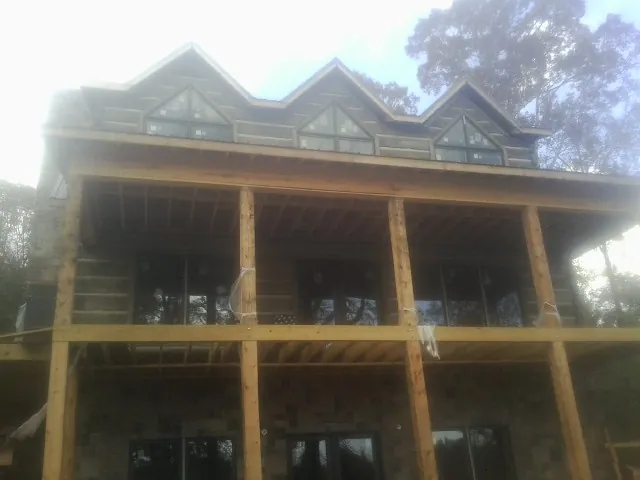 Dormers and porch framing on a large log home under construction — Roof Coating work by our crew in Crisfield