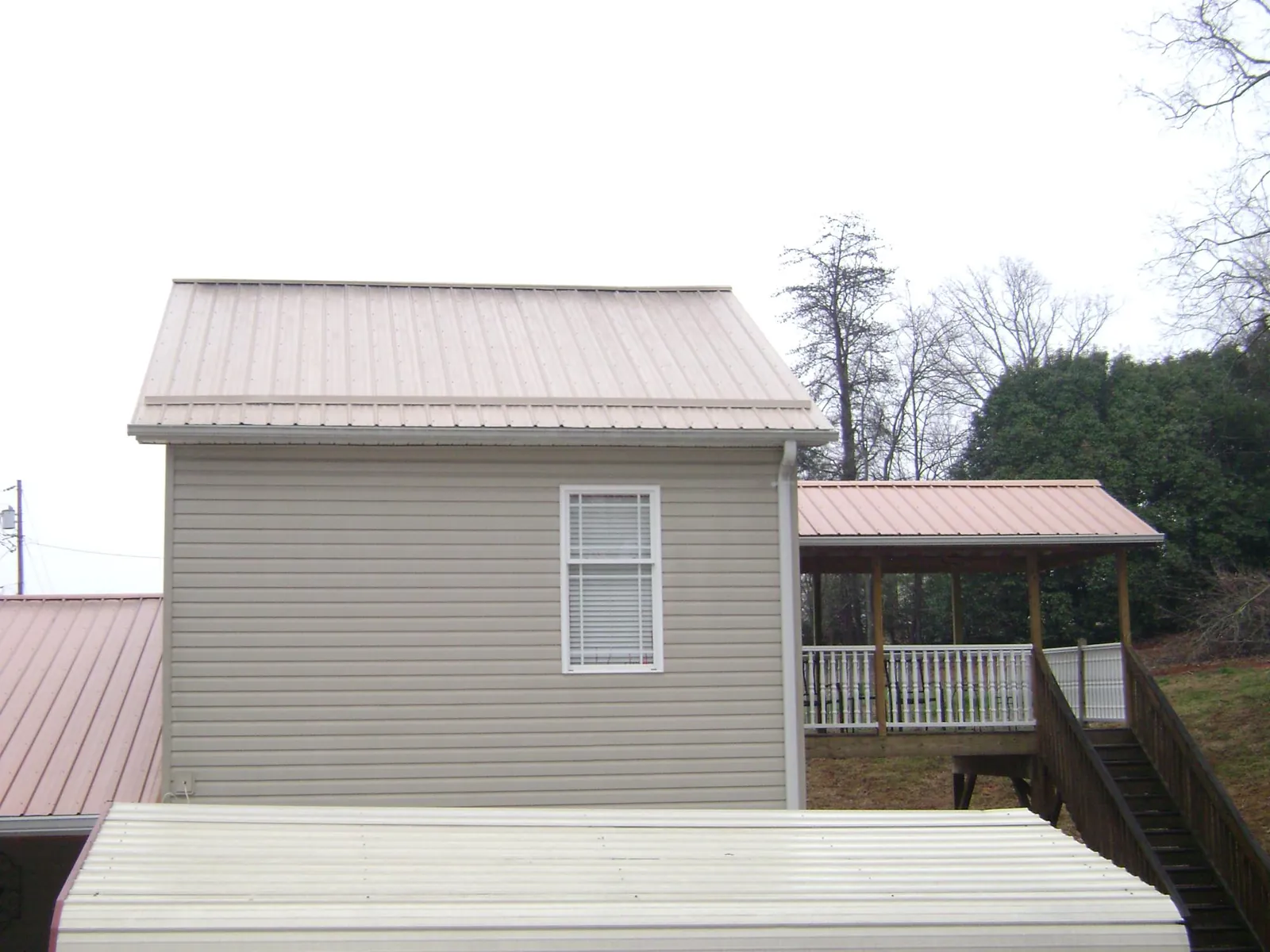 Tan metal roofs on a two story addition and attached porch, from a Roof Replacement job in Crisfield