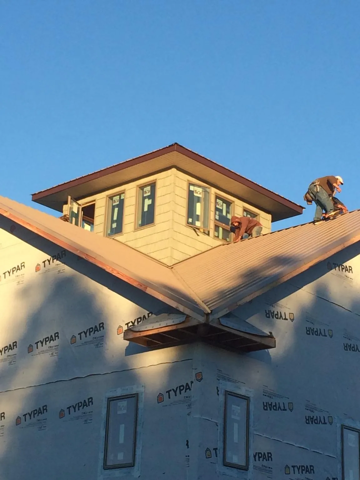 Roofers working around a rooftop cupola on a new metal roof at sunset — Roof Waterproofing in Crisfield by Roofing Brothers